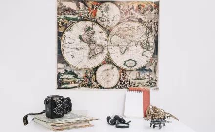 como pendurar quadro decorativo de mapa-múndi pendurado na parede acima de mesa com câmera vintage e objetos de decoração.